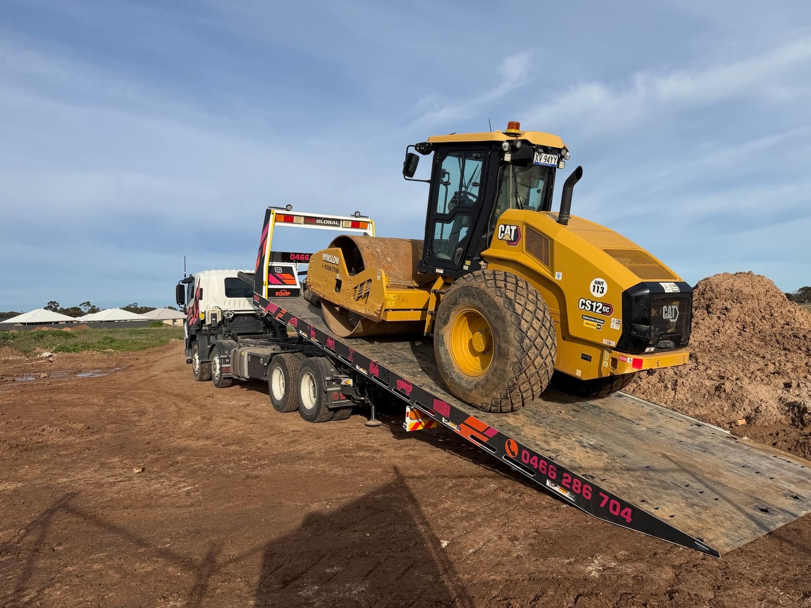 CAT roller unloading from tilted tray during machinery transport in Adelaide